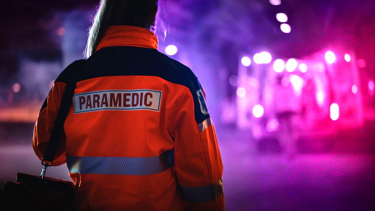 Paramedic is walking toward ambulance, purple light