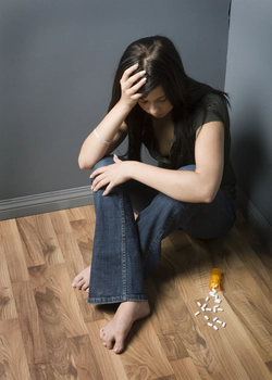 Young woman addicted to pills, sits on a floor
