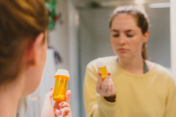 Teenager holding a prescription drugs bottle. 
