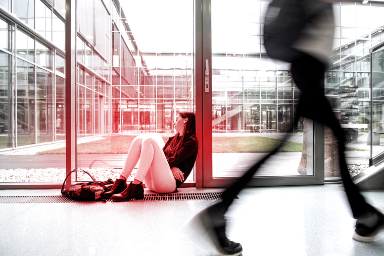 College girl sits on a college hallway floor under drug effects.