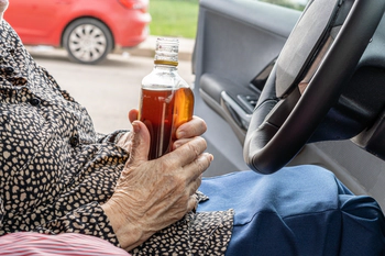 Elderly driver with an alcohol bottle.