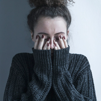 Grey tinted photo of woman in sweater having a difficult time