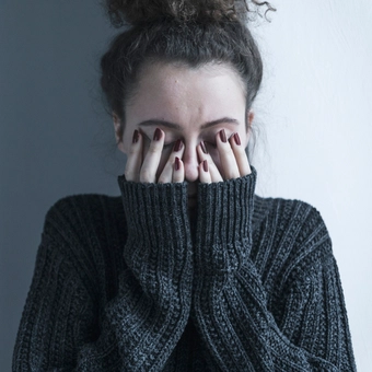 Foto en tonos grises de una mujer con suéter pasando un mal momento