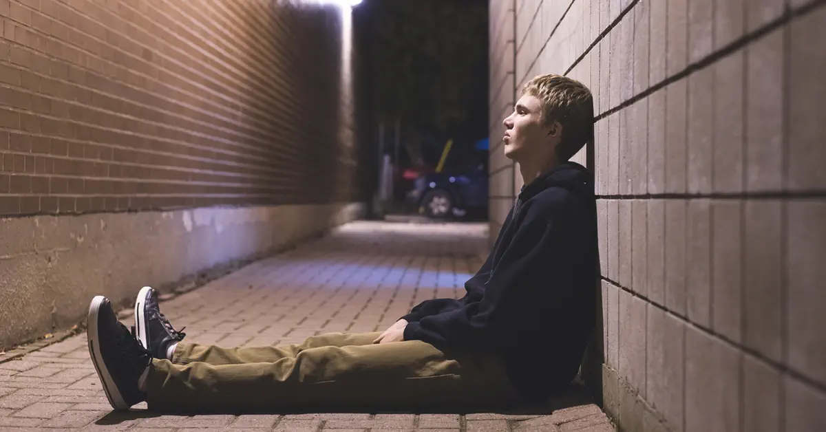 Drug user sitting in an alley