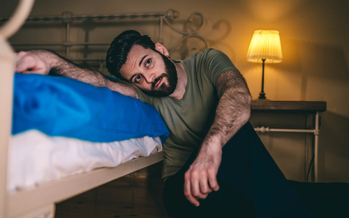 Man in pain leaning on bed